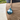 Green leather golf ball holder attached to a belt, worn on pants, with a golf ball securely placed inside. The holder features a smooth leather texture, precise stitching, and a compact design for convenient access