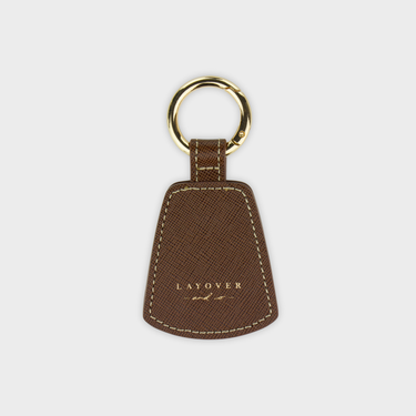 Brown leather hat clip holder with gold ring on a white background