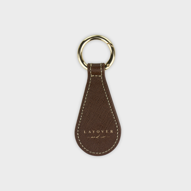 Brown leather hat clip holder with gold ring on a white background