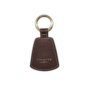 A premium brown leather hat holder from Layover & Co., featuring a textured finish, gold-embossed branding, and a sturdy gold keyring. Designed with a magnetic closure for securely holding hats on bags or belts.