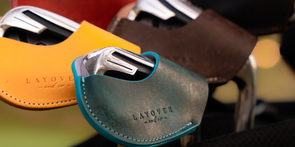 Close-up of leather iron covers with 'Layover and co' branding on a blurred background